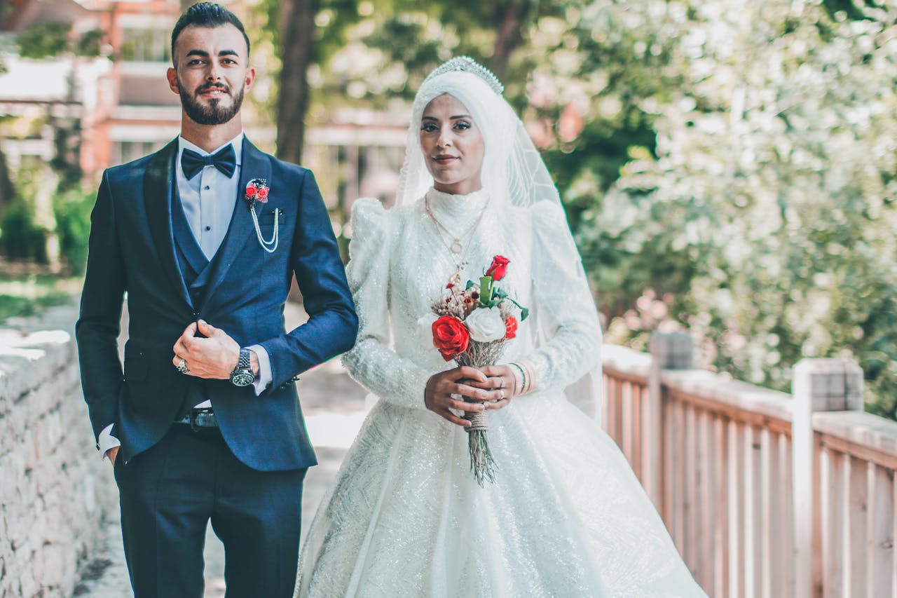 A man and woman in wedding attire standing on a bridge