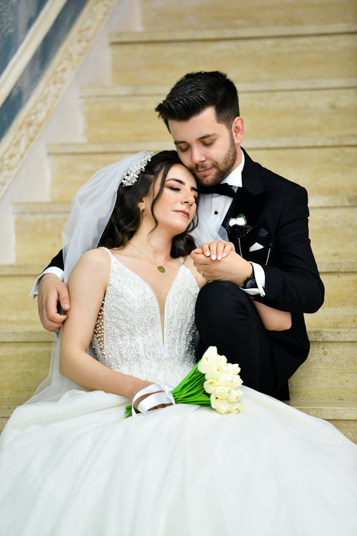 A bride and groom are sitting on the stairs